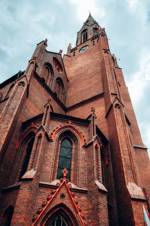 Free A low angle shot of a gothic church tower facade in Poznań, illustrating historic architecture and religious significance. Stock Photo