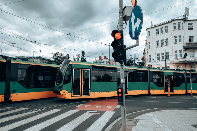 Green and yellow trams at a city intersection in Poznań, capturing urban transportation.