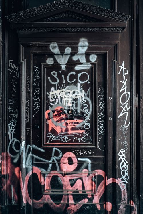 Free A worn wooden door covered in colorful urban graffiti, showcasing street art culture. Stock Photo