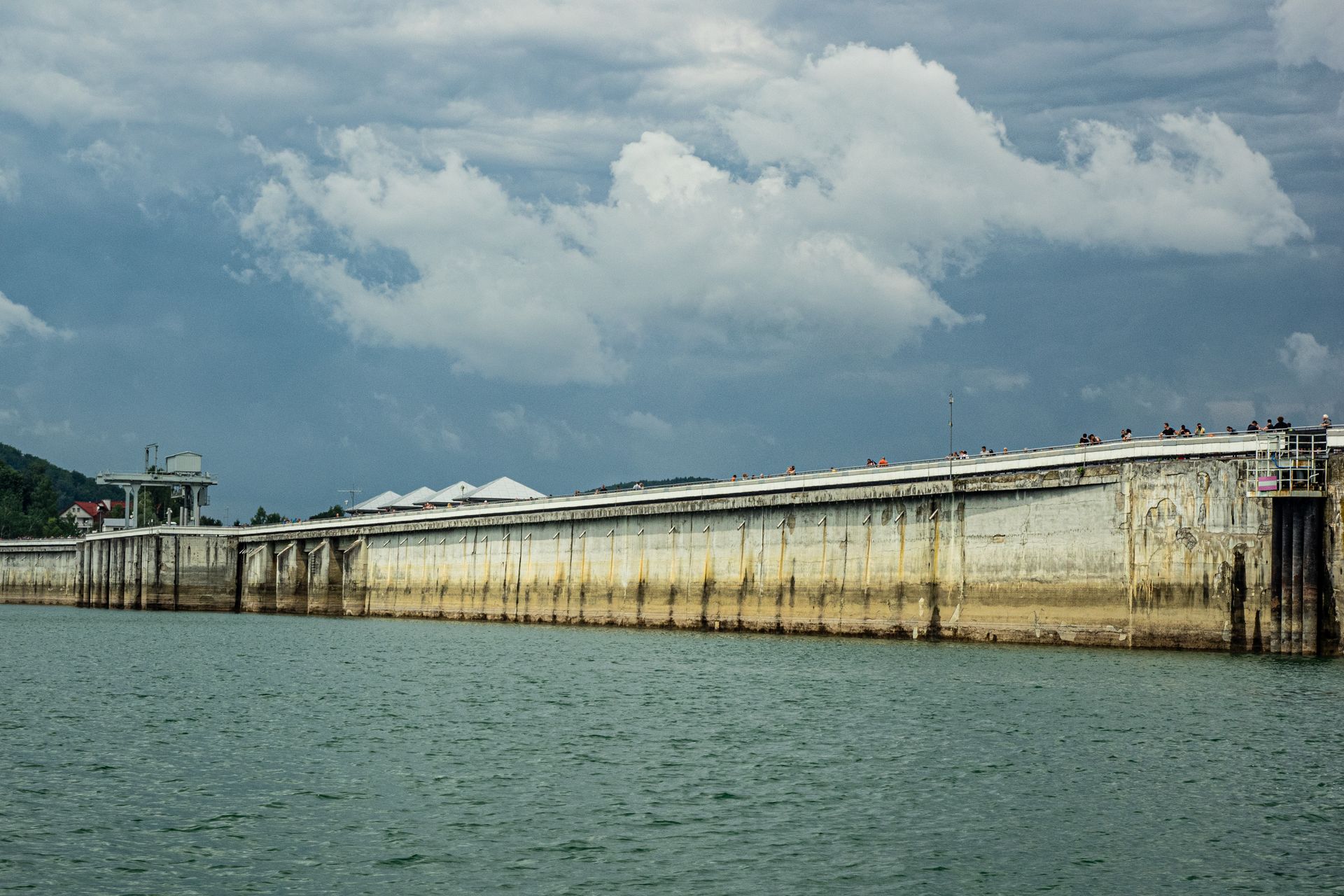 Large concrete dam wall with reservoir water behind it