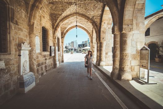 A woman walks through historic stone arches in Kalo Chorio, Nicosia, Cyprus.