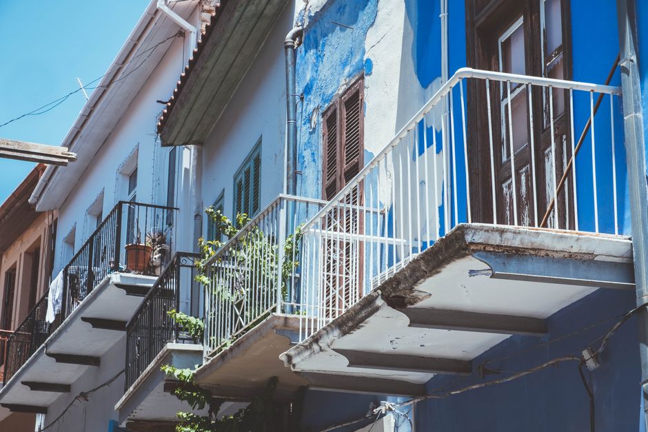 Weathered Cyprus balconies with peeling paint and water-damaged concrete soffits showing visible moisture deterioration.