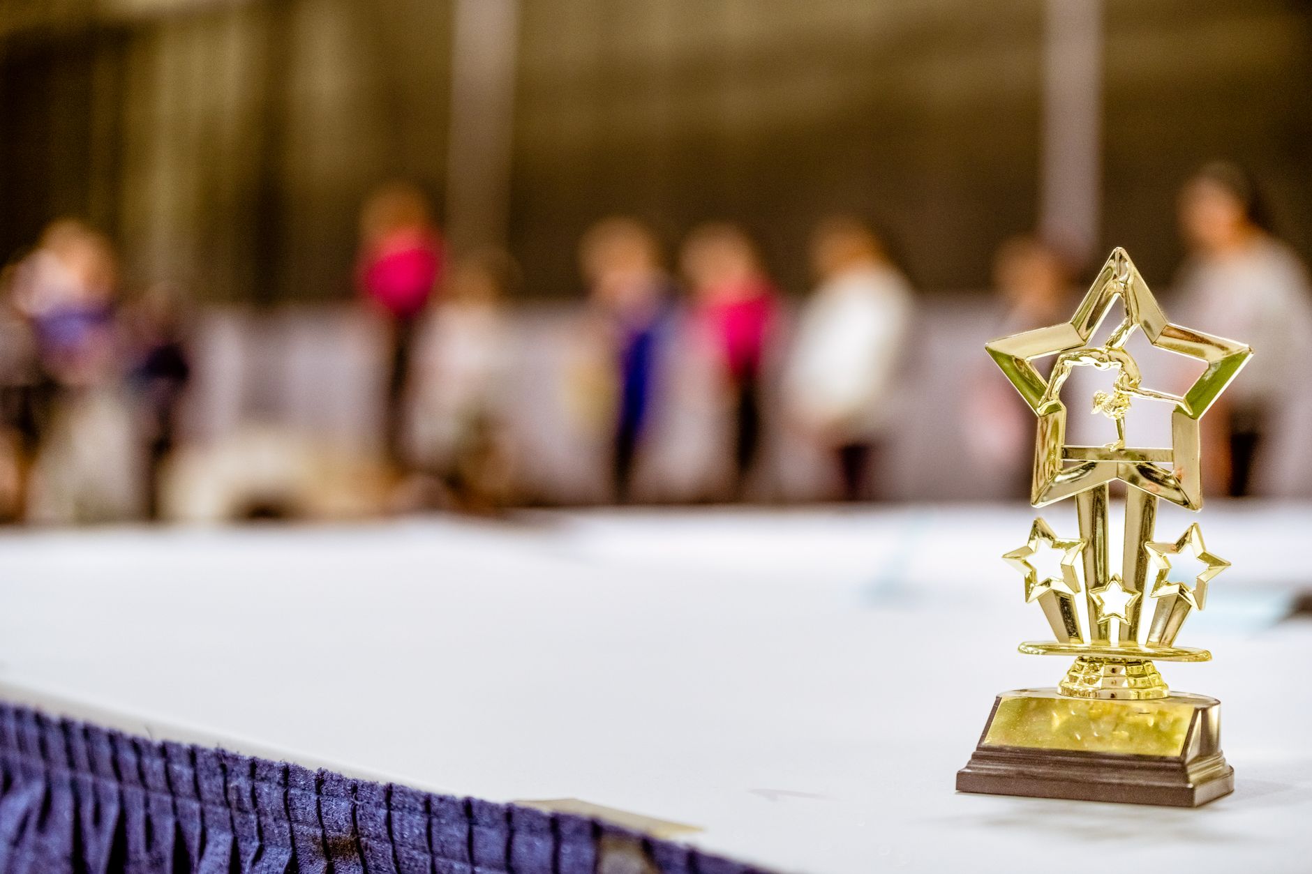 Star-shaped trophy on a table with blurred people in the background at an indoor event.