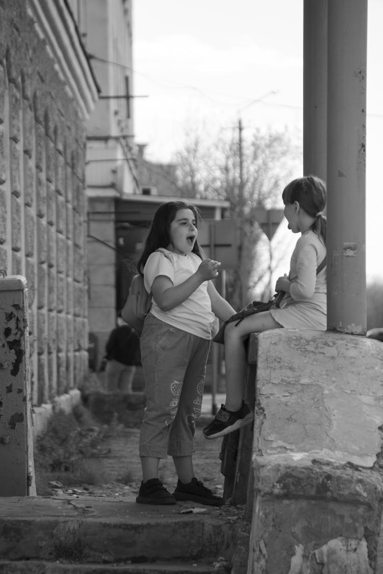 A Girl Sitting On The Concrete Wall While Showing Her Tongue 