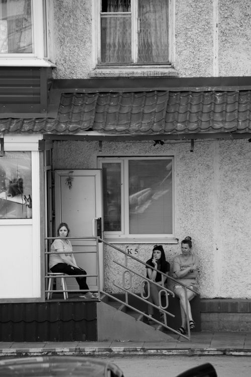 Free A black and white photo of three women relaxing outside an urban residential building. Stock Photo