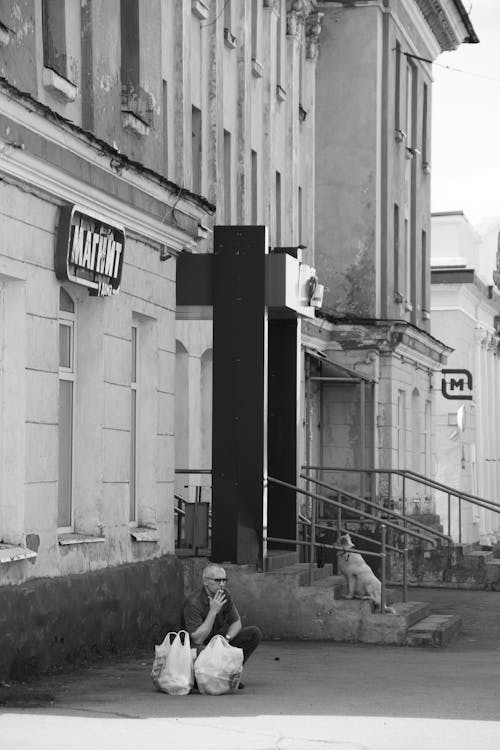 Grayscale Photo of a Man Smoking Outside the Building 