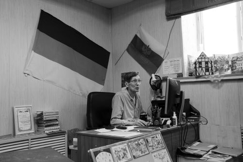 Free Monochrome image of a man working at an office desk with flags in background. Stock Photo