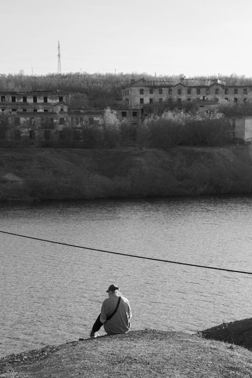 Free Black and White Photo of a Person Sitting Alone by the Water Stock Photo