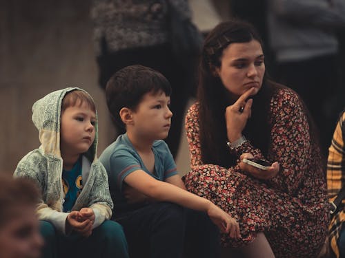 Photo of a Woman in Floral Dress Sitting Beside Two Boys