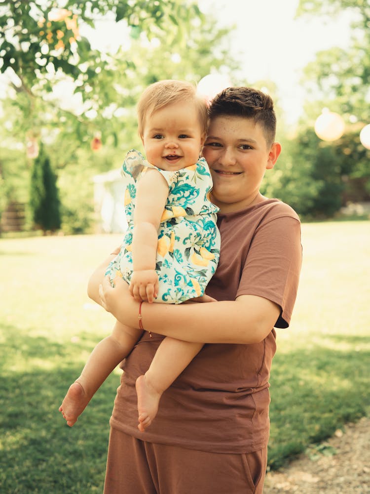 A Boy Carrying A Baby Girl