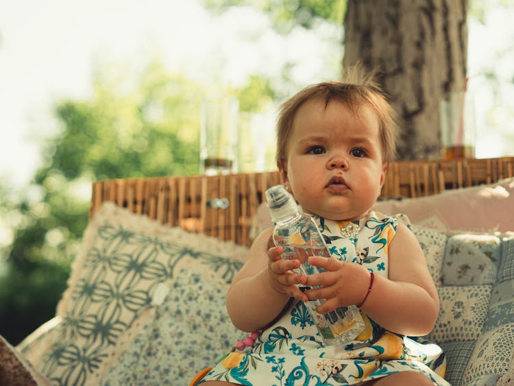 A Baby Girl Holding A Bottle