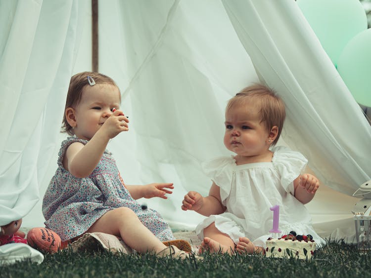 Babies Sitting On A Grassy Ground Near 