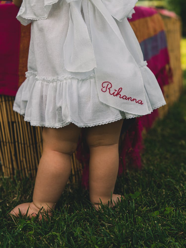 Photo Of A Baby Legs In A White Dress With A Rihanna Sign 