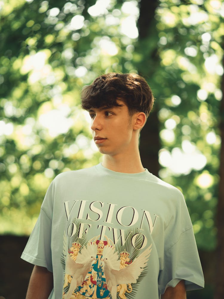 Teenager Wearing A T-Shirt With Graphics Posing Against A Tree