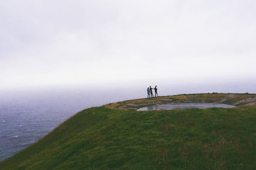 Three friends stand on a hilltop with ocean views in Ponta Delgada, Azores.