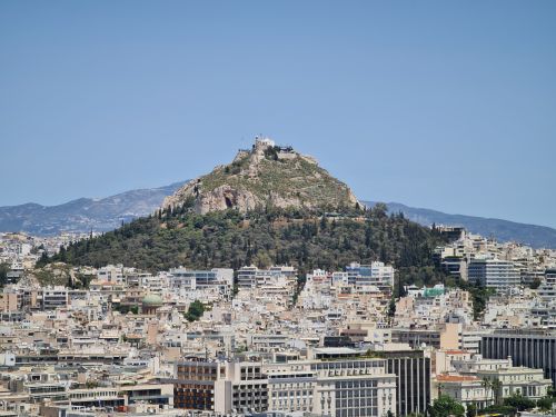 Free A stunning view of Lycabettus Hill rising above the Athens cityscape under a clear blue sky. Stock Photo