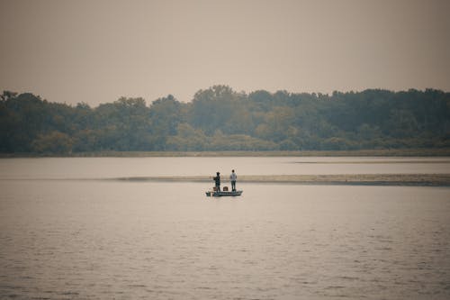 People Fishing while Standing on a Boat