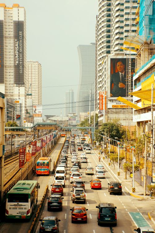Free High-rise buildings and busy city traffic with buses and cars on a vibrant day. Stock Photo