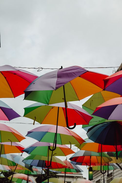 Free Colorful umbrellas hanging overhead in a city street, creating a vibrant outdoor canopy. Stock Photo
