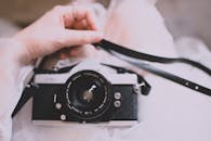 一位女士手持经典胶片相机的特写，展现了老式摄影设备