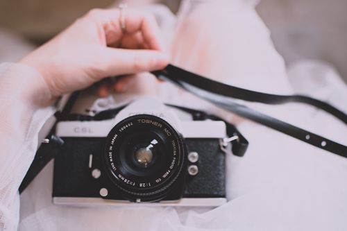 Free Close-up of a classic film camera held by a woman's hand, showcasing vintage photography equipment. Stock Photo