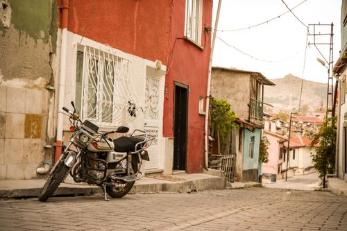 Free A motorcycle parked on a quaint street in Afyonkarahisar, Türkiye, showcasing vibrant architecture. Stock Photo