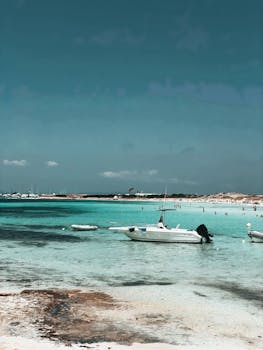 Idyllic beach scene in Formentera, Spain showcasing motorboats and turquoise waters, perfect for a summer getaway.