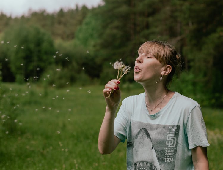 Woman Blowing Dandelion Flowers