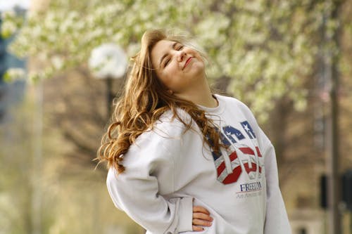 Selective Focus Photography of Posing Woman Wearing White Usa Crew-neck Long-sleeved Shirt