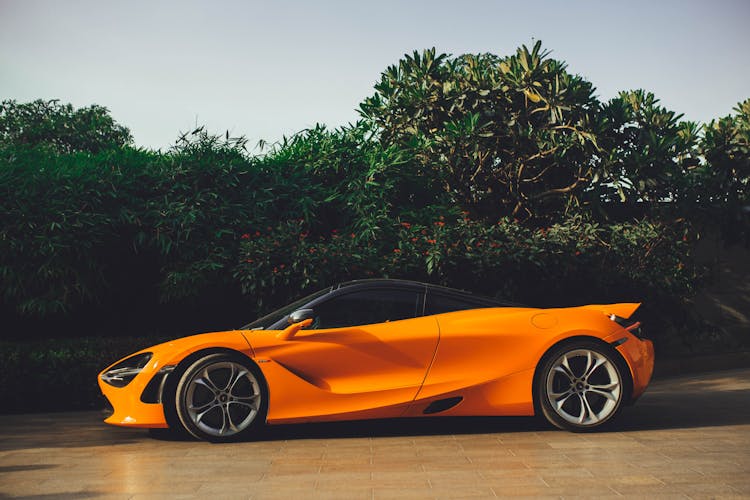 Orange Mclaren Car Parked Near Green Plants