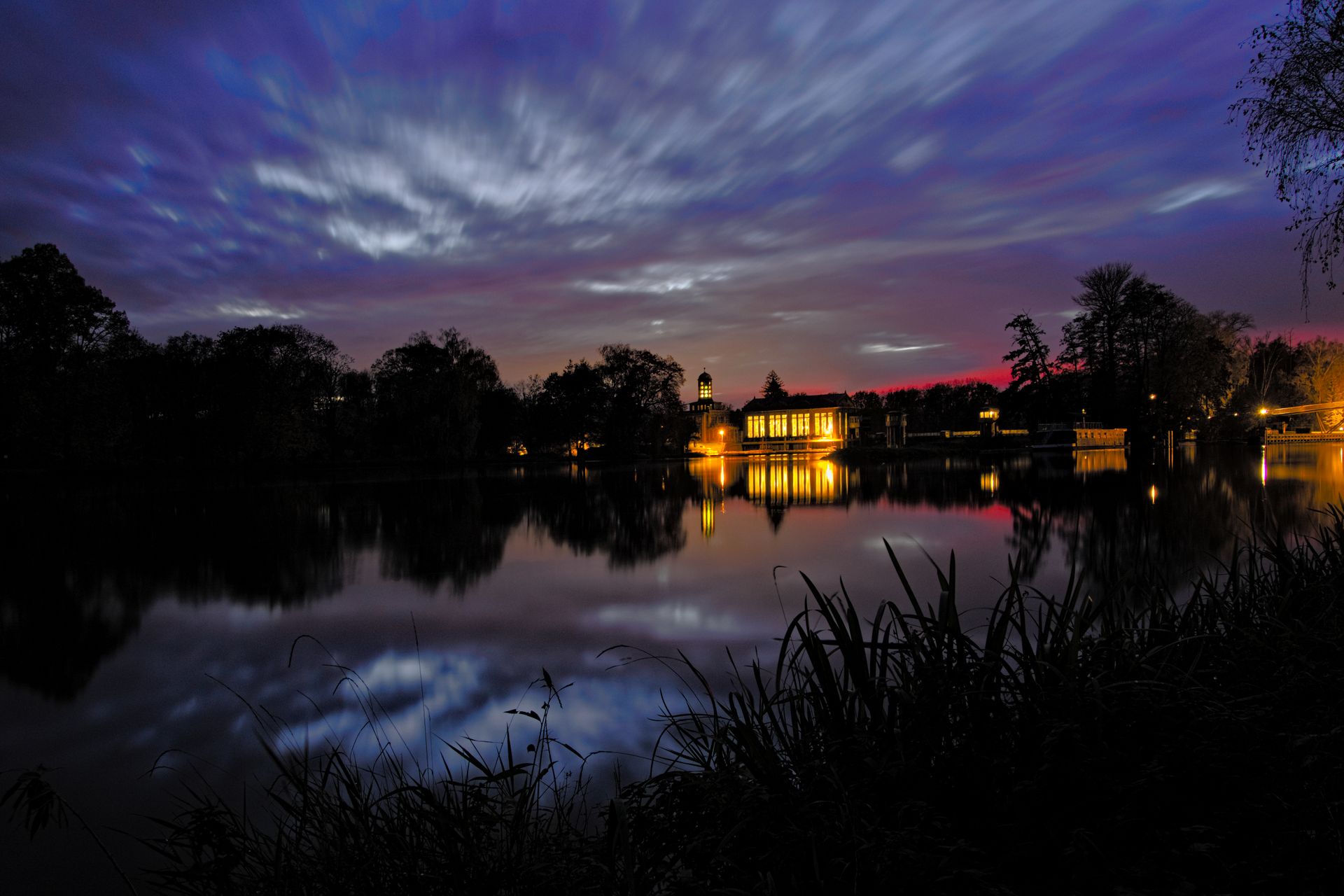 Serene twilight view of a Czech lake with lit architecture reflecting on water.