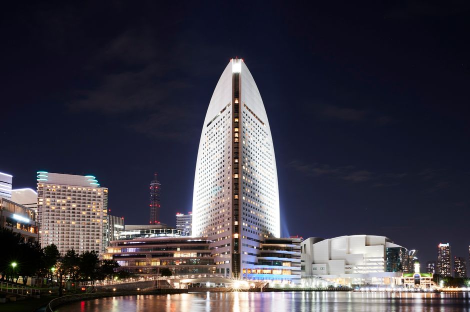 Illuminated Yokohama skyline featuring Minato Mirai skyscrapers at night with reflections.