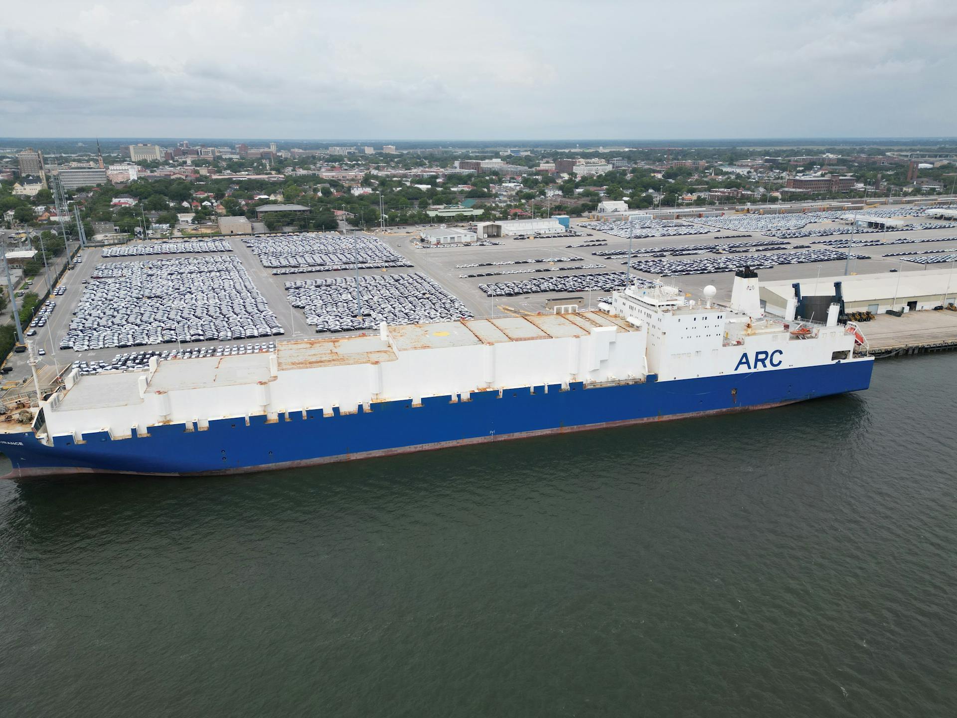 Aerial view of a massive cargo ship docked at Charleston Harbor, showcasing industrial and port activity.