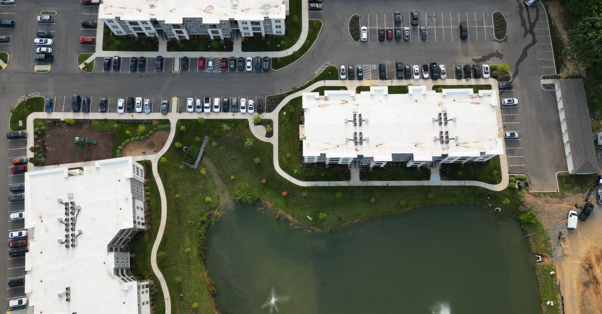 Drone view of apartment buildings, parking lots, and pond in Knoxville, TN.