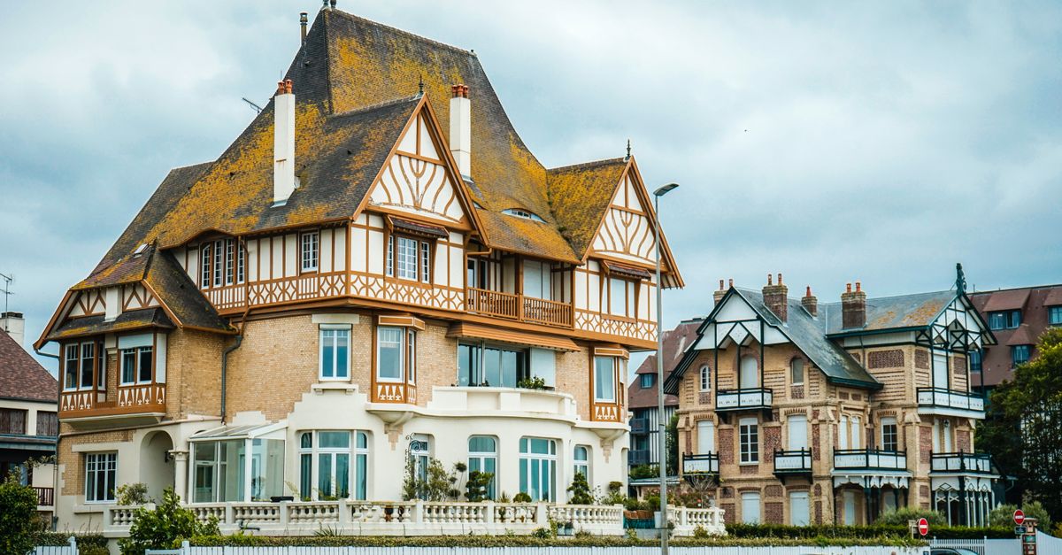 Elegant Tudor-style mansion set against a cloudy blue sky, showcasing architectural beauty.
