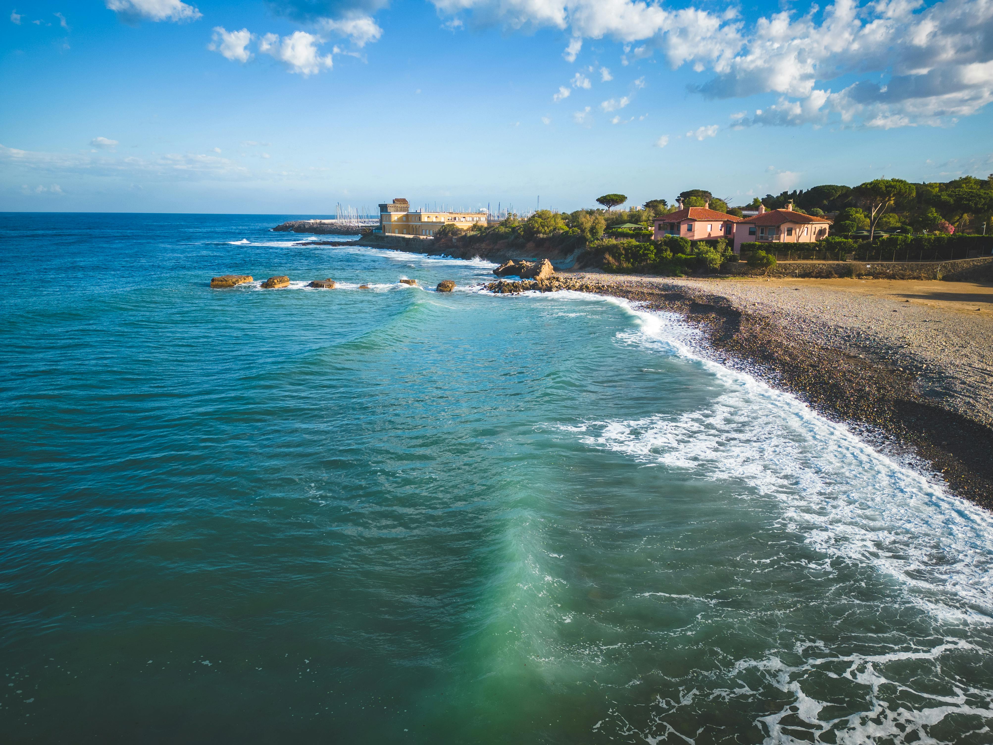 Explore a tranquil Mediterranean shoreline with calm waves and a clear, blue sky.