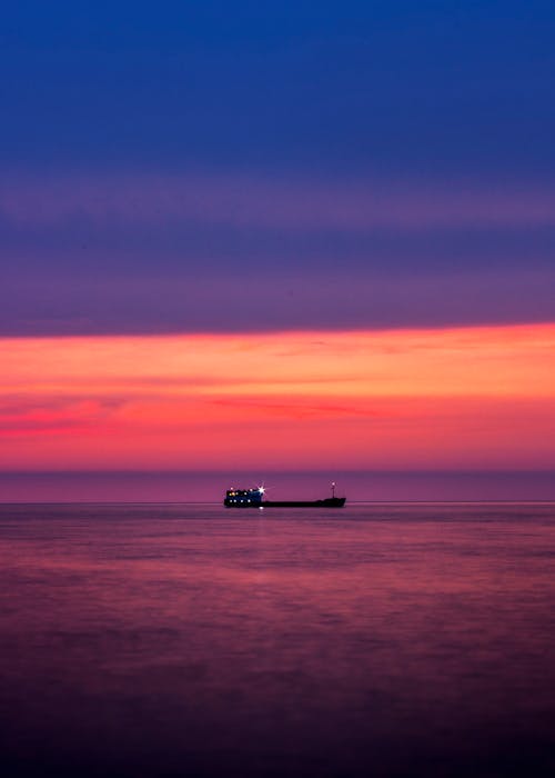 Silhouette of Ship on Sea in Sunset Scenery
