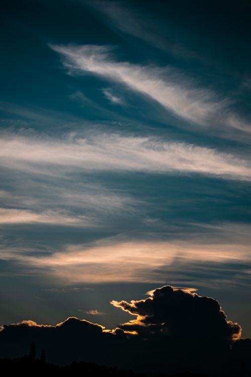 Free Silhouette of dark clouds against a vibrant twilight sky with streaks of light. Stock Photo