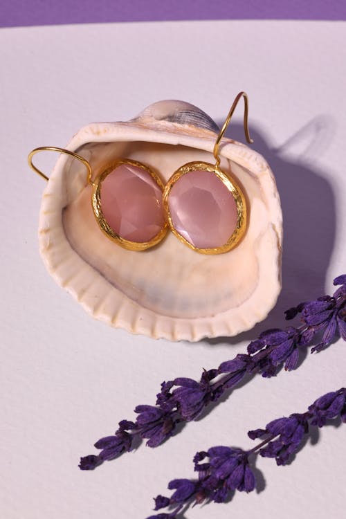 A Pair of Pink Gemstone Earrings on a Seashell
