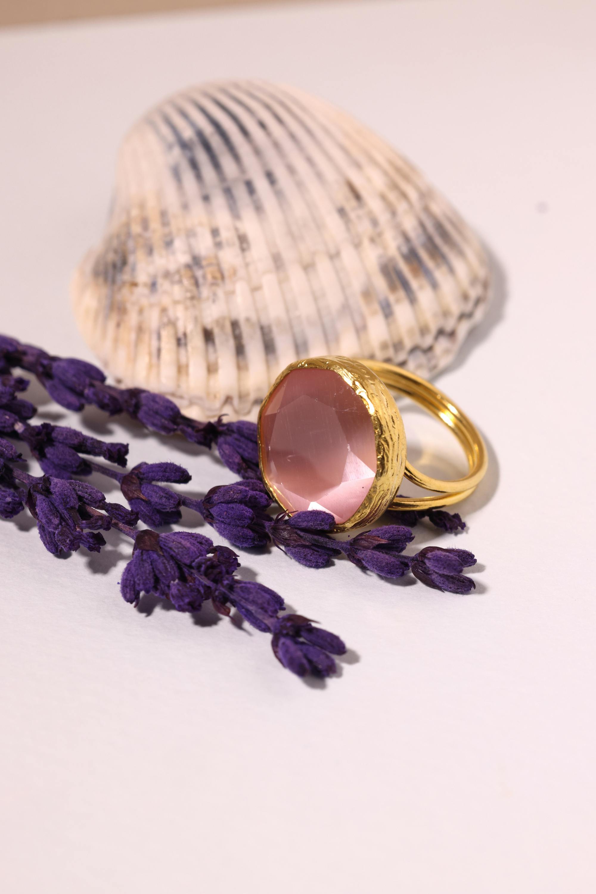 photo of a composite of lavender a seashell and a golden ring with a pink crystal