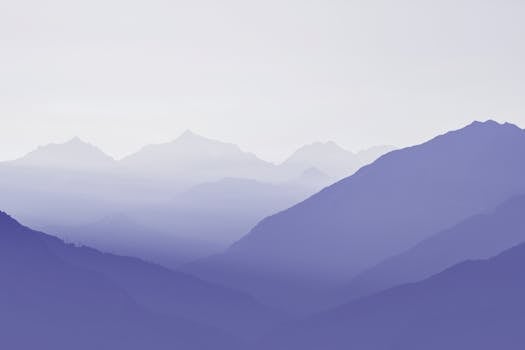 Calming view of layered misty mountains with a purple hue, perfect for tranquil and peaceful themes.