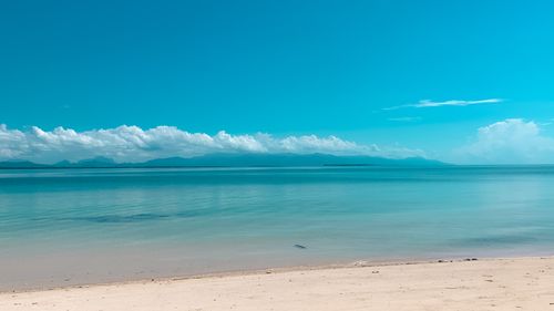 Free Idyllic beach scene with turquoise waters, clear blue sky, and distant mountains in view. Stock Photo