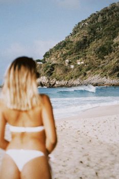 Back view of a woman in bikini enjoying a sunny beach in Rio, capturing the essence of a tropical getaway.