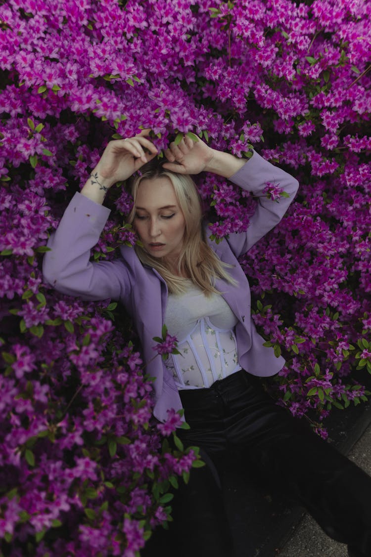 Blonde Woman Fashion Model Leaning On Rhododendron Shrub