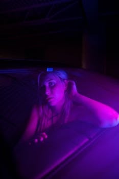A woman in neon purple light, creating a moody atmosphere in a dimly lit indoor setting.