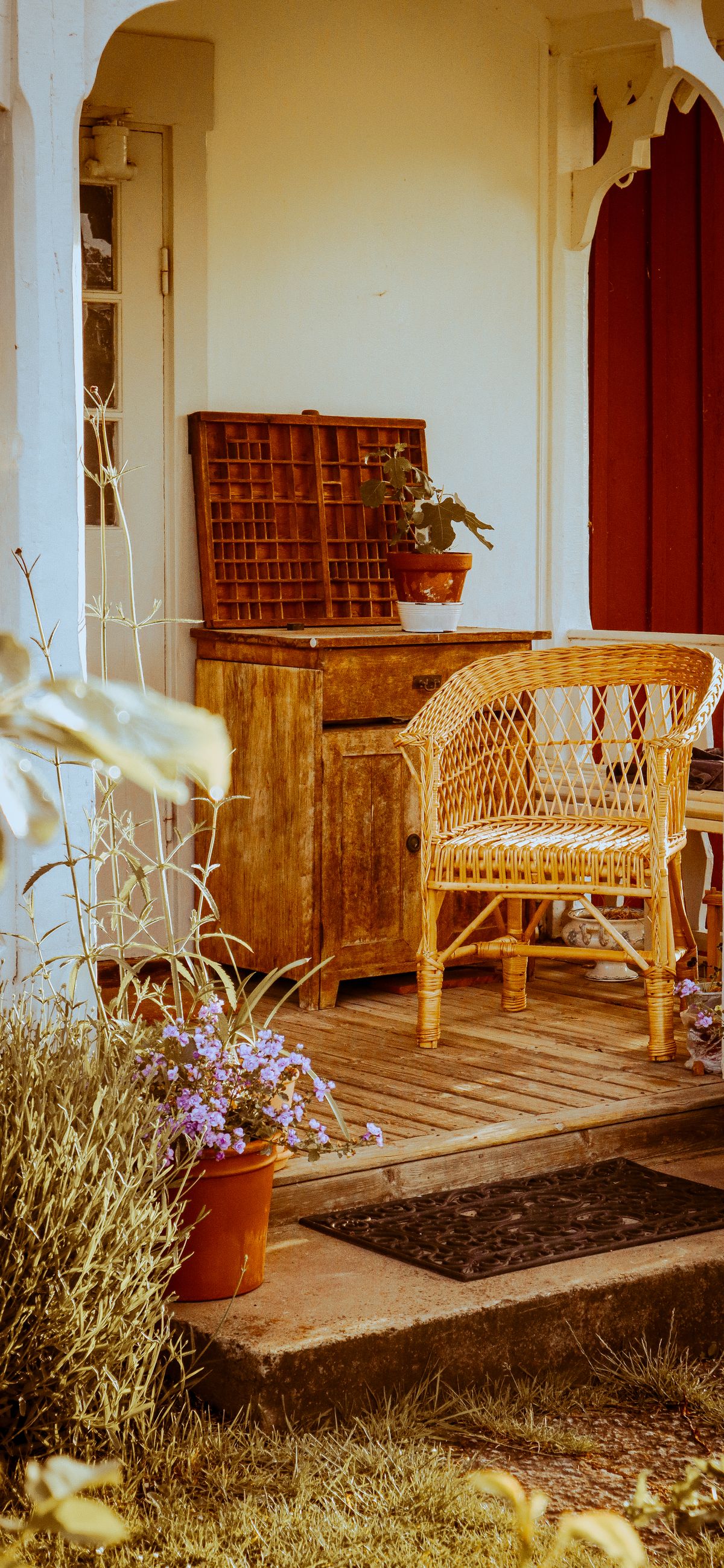 Cozy porch with a wicker armchair and wooden desk, perfect for relaxation at home. Stock Photo.