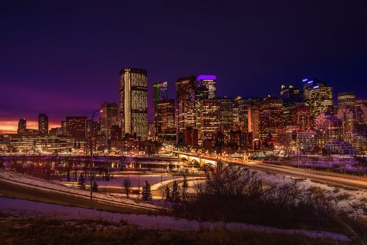 Stunning view of the illuminated Calgary skyline featuring skyscrapers and vibrant city lights at dusk.
