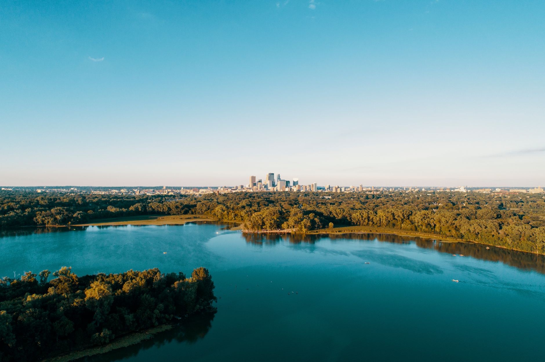 Stunning aerial view of the Minneapolis skyline with lush green landscape and lakes during summer.
