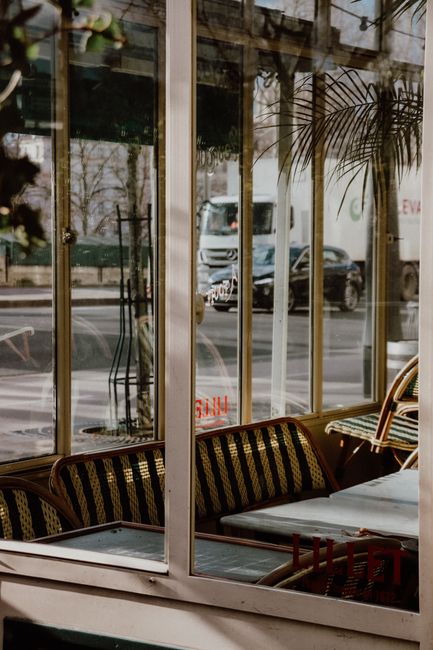Explore an elegant Paris café interior with vintage furniture and city view through glass windows.