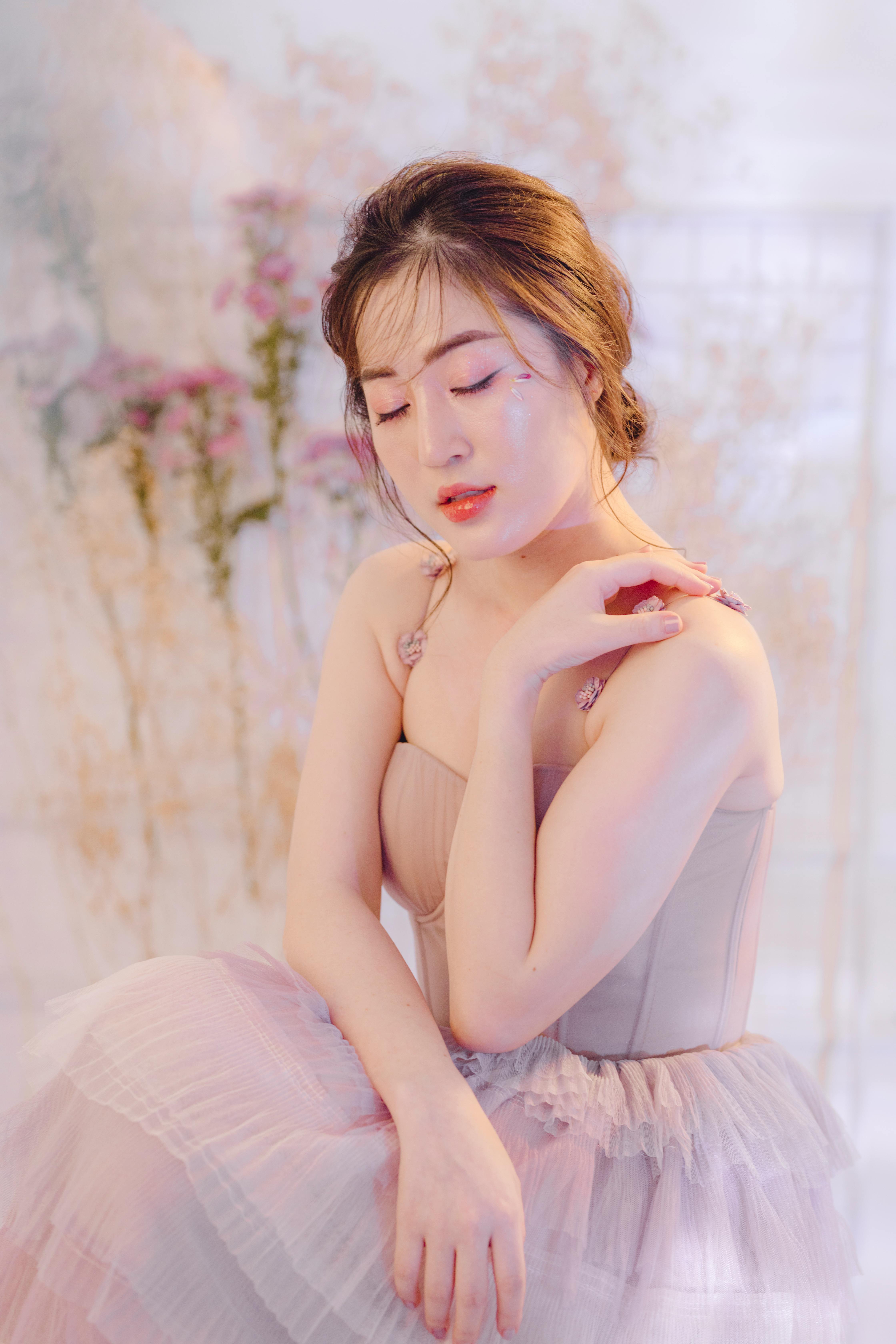 Graceful woman posing in a pink tulle dress with floral background.